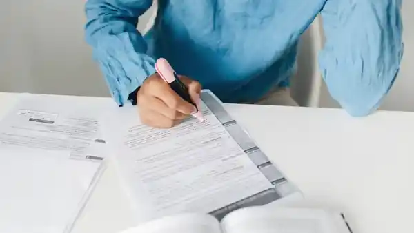 A person marking a printed document with a highlighter.
