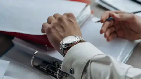 Hands reviewing paper documents with a pen.