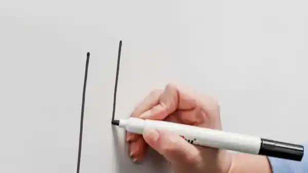 A hand drawing lines on a whiteboard with a black marker.